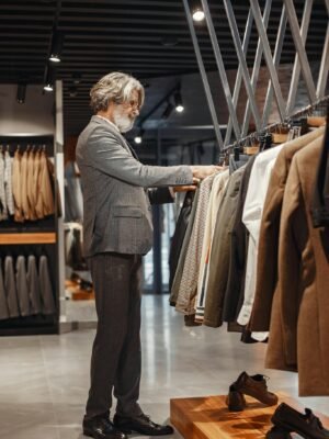 A man browsing clothes in a modern boutique store with a variety of suits on display.