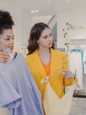 Two stylish women picking outfits together in a trendy clothing store.